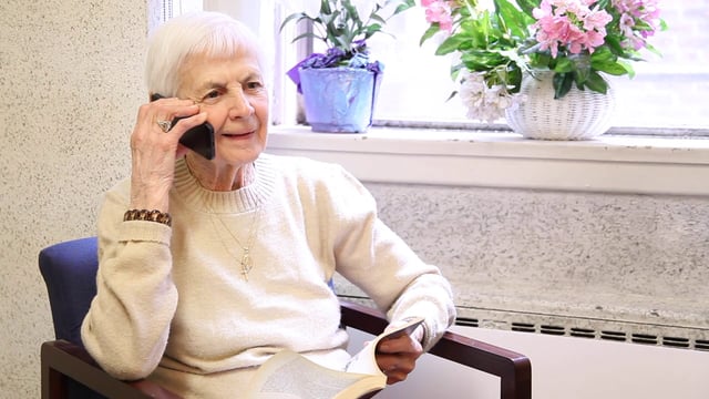 elderly lady answering call in front of bright window